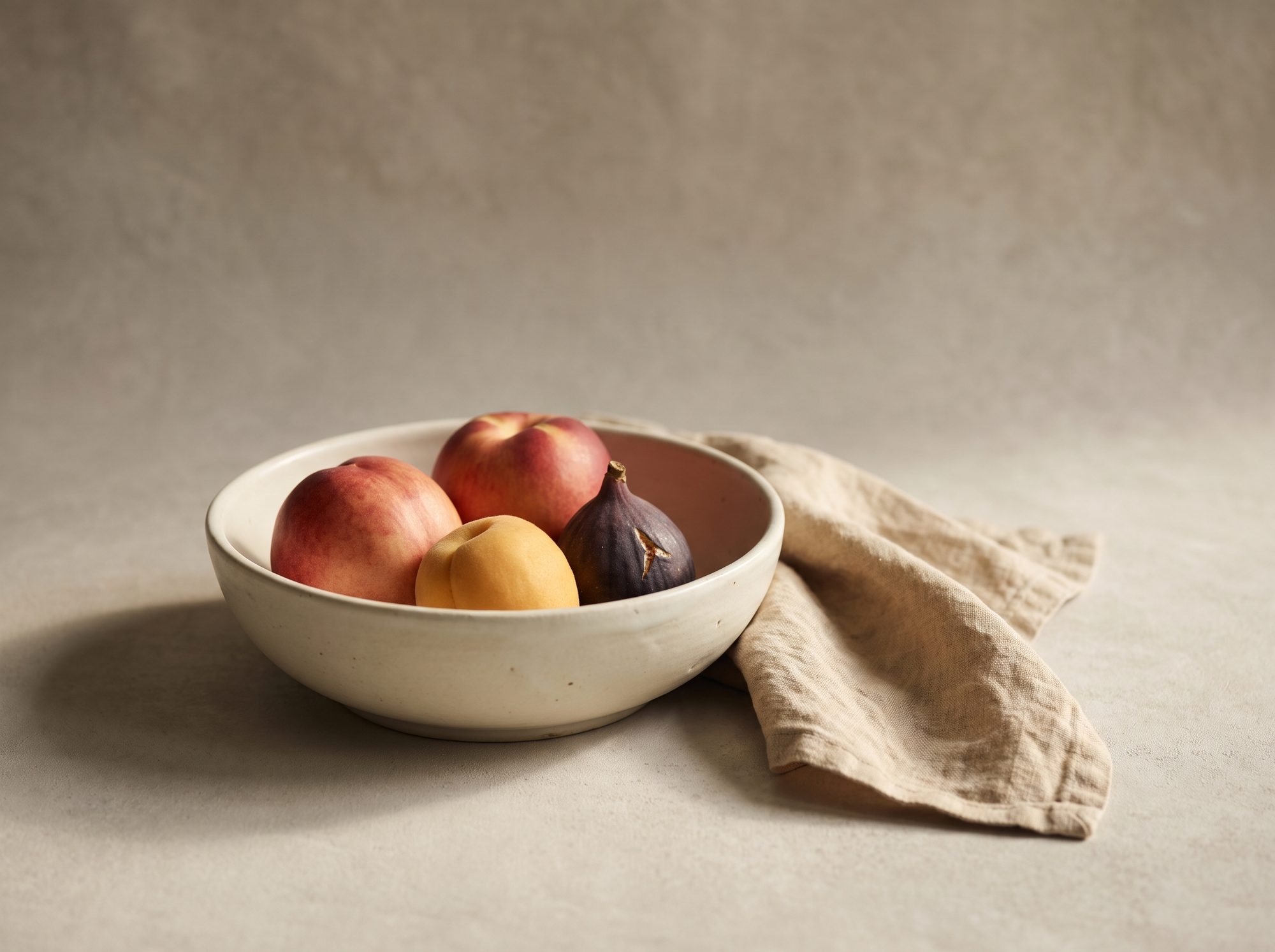 A bowl of ripe stone fruit on soft linen, nourishment as information