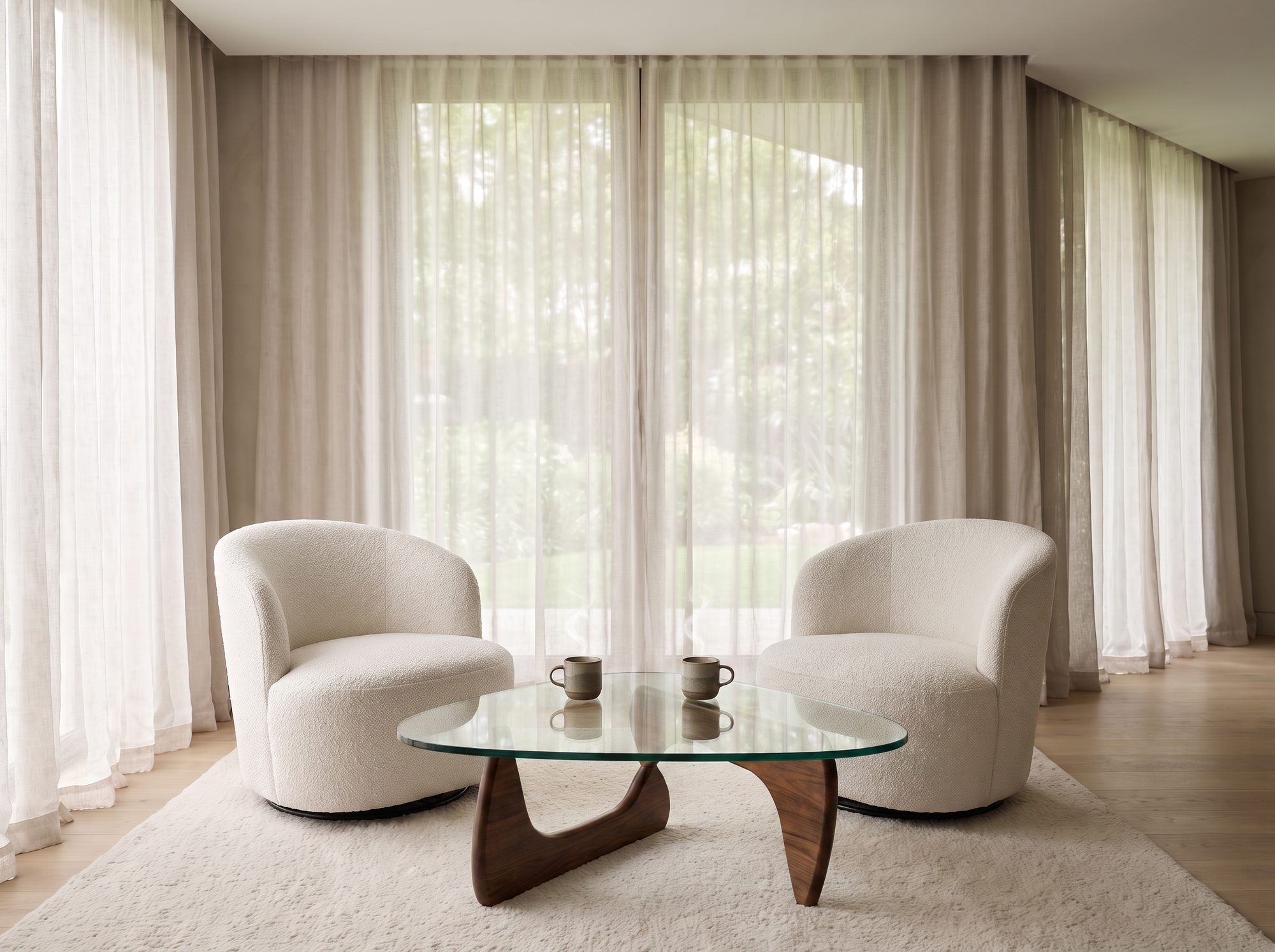 Two soft cream chairs around a sculptural walnut and glass coffee table with two warm cups of tea, two ways to work together